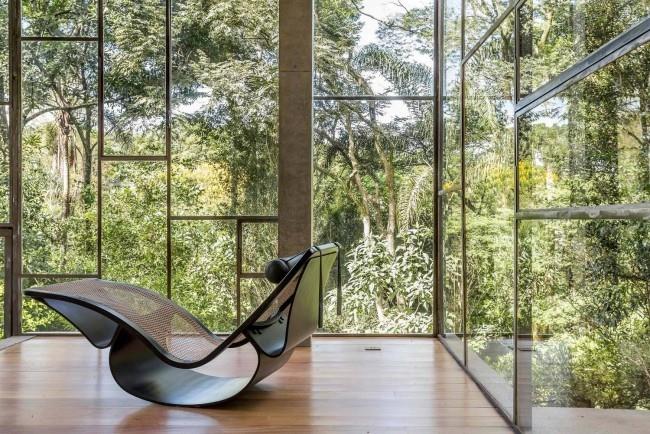 Une maison moderne en verre et béton dans la forêt tropicale construit des fauteuils à bascule chics avec un mélange de design moderne et rétro