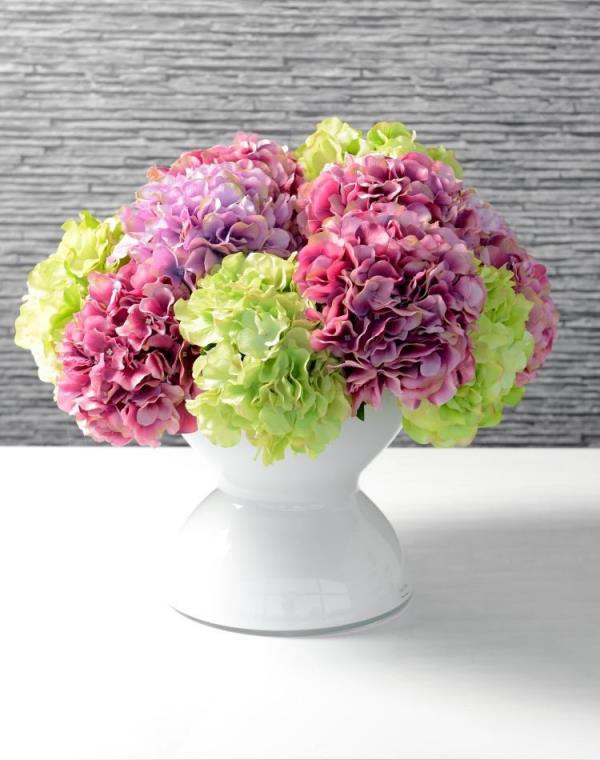 Fleurs d'hortensia rose de différentes couleurs disposées dans un vase blanc