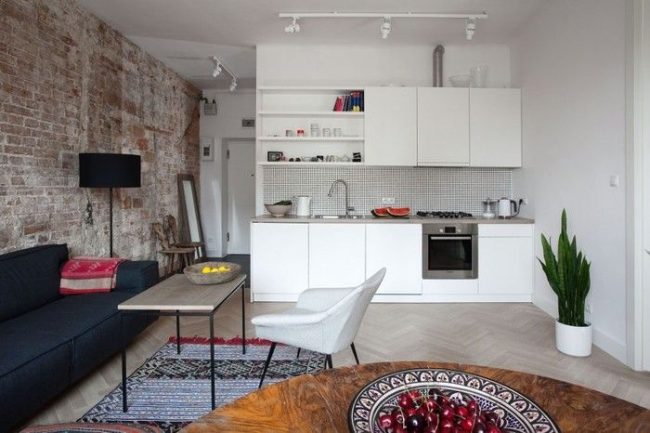 Контрастът на бели и тухлени стени в дизайна на едностайна кухня студио