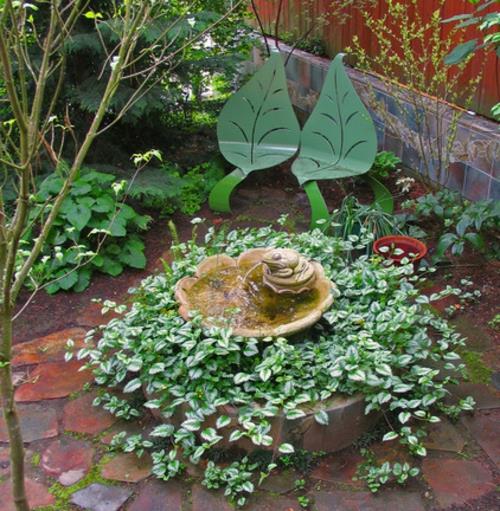 Plantes luxuriantes dans la fontaine d'eau à feuilles caduques du jardin bien entretenu